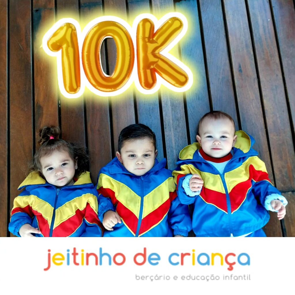 Três alunos da Escola Jeitinho de Criança de uniforme deitados no deck de madeira, com balões dourados formando 10K