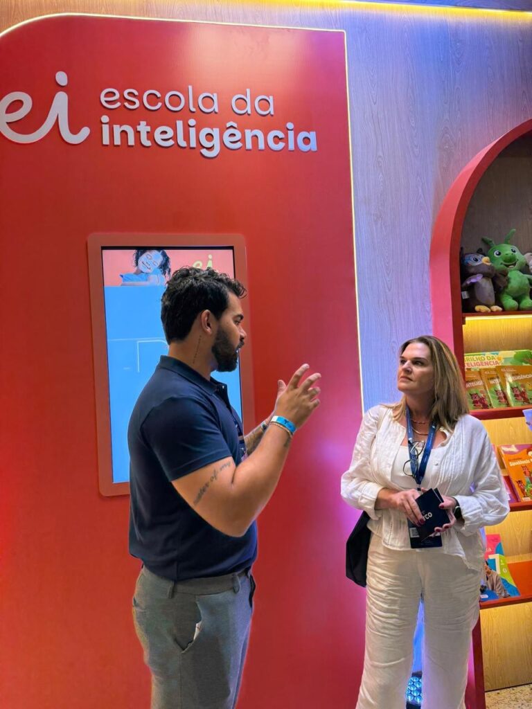 Gestora da Escola Jeitinho de Criança conversando com um representante no estande da Escola da Inteligência durante o fórum